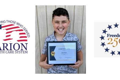 Smiling person with framed certificate, logos for Marion and Freedom 250.