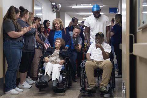 Group of people in hospital hallway with two people in wheelchairs.